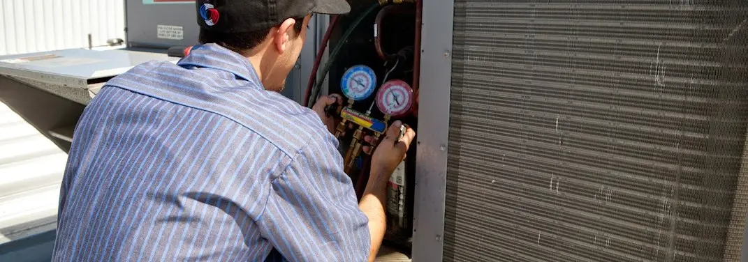 HVAC technician servicing a condenser unit in San Jacinto